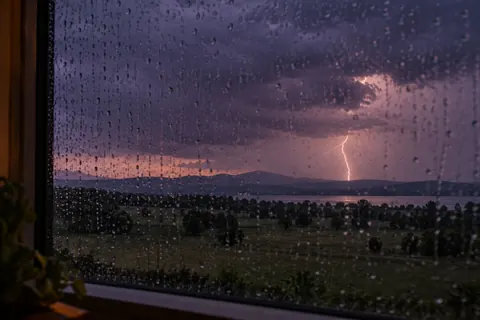 Distant lightning seen through a rain-covered window