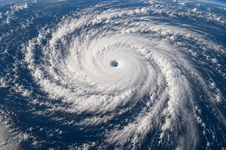 Conceptual aerial view of a hurricane with a clear eye surrounded by white spiral clouds over blue ocean