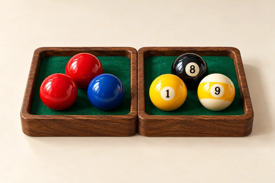 Selected unnumbered red and blue snooker balls beside numbered 1, 8 and 9 pool balls in green-lined wooden trays
