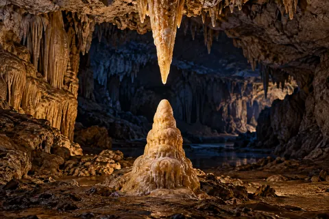 A pointed stalactite above a rounded stalagmite in a limestone cave