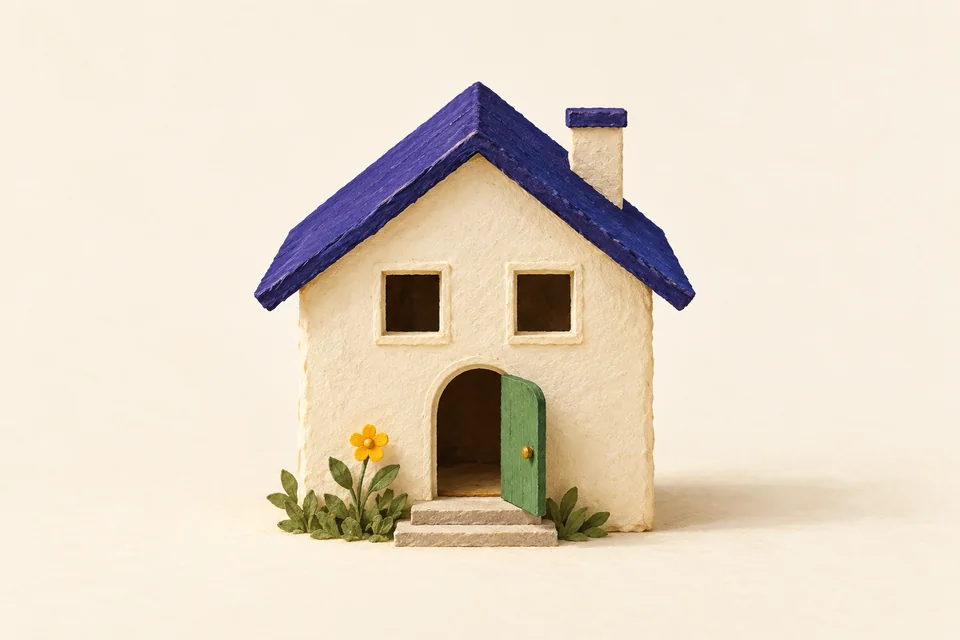 A cream miniature house with two square windows above an arched doorway, suggesting a surprised face