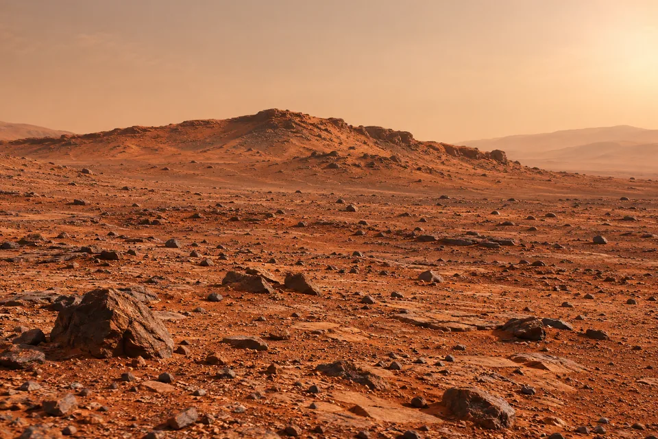 An imagined rusty-red Martian plain beneath a pale dusty sky