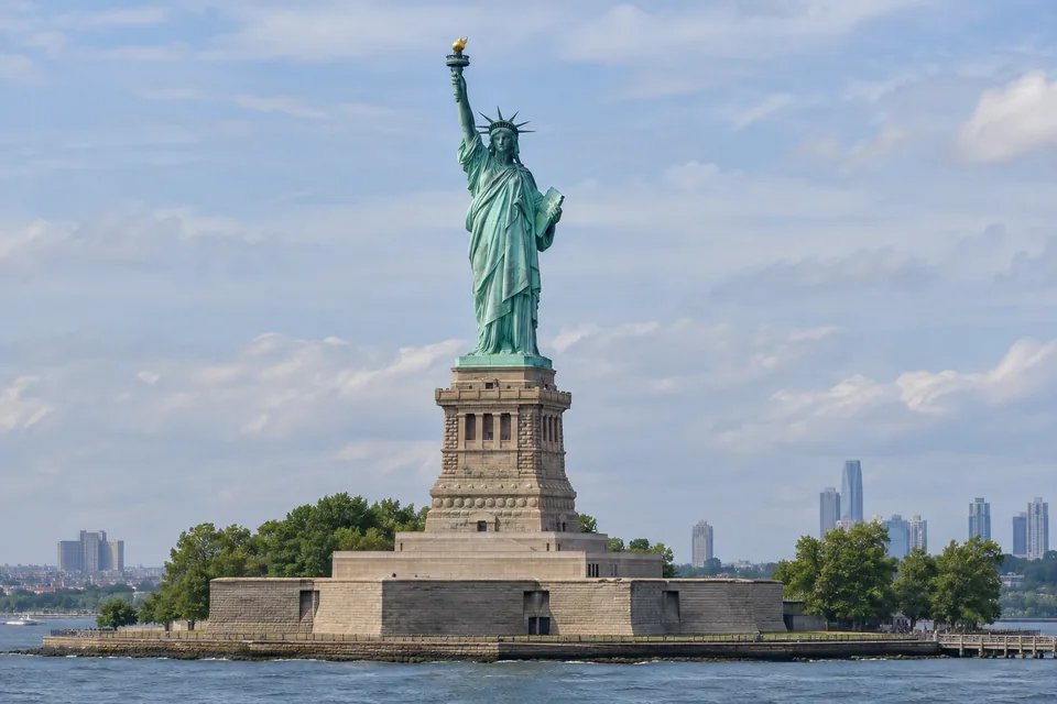 The green Statue of Liberty rises above its pedestal beside New York harbour